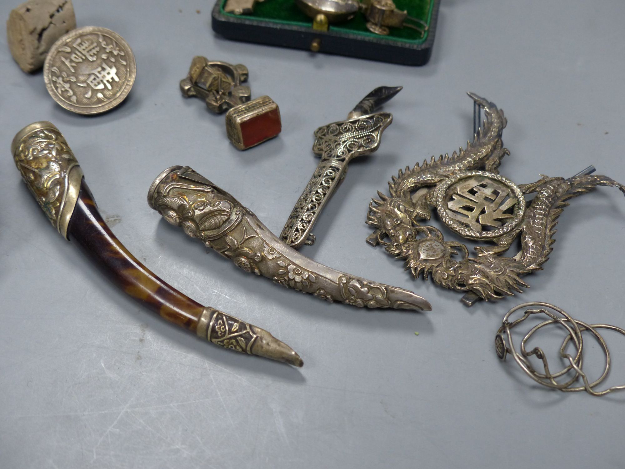 Assorted Chinese white metal items including a menu holder, nail guard, charms, brooches etc.